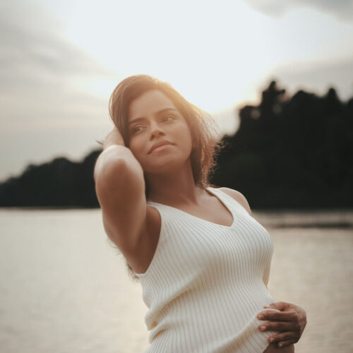 Expectant mother smiling while gently holding her baby bump.