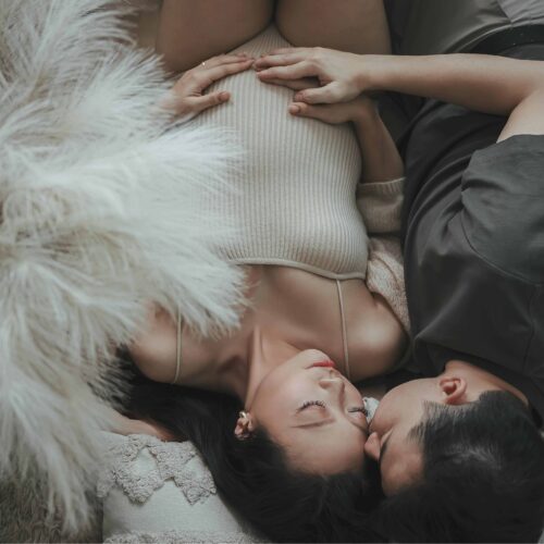 Couple in love embracing on bed during pregnancy shoot