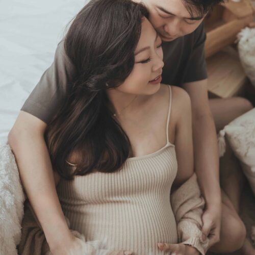 Two people in nightwear embracing, exuding happiness and romance at maternity photoshoot.