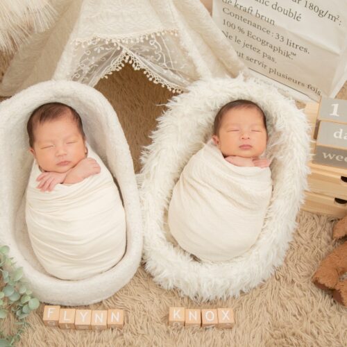 A close-up shot of a sleeping newborn babies wrapped in a soft blanket.