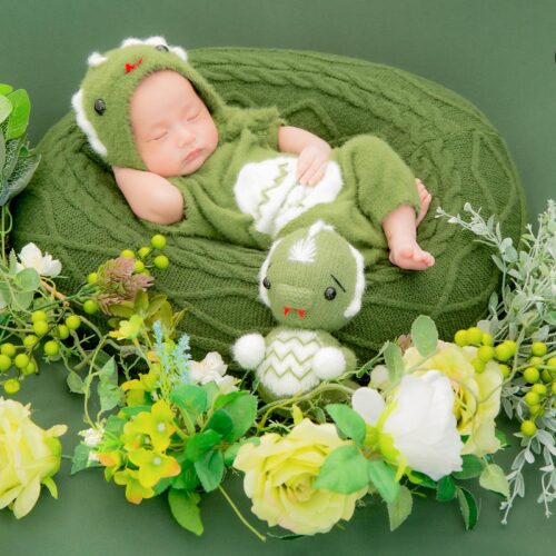 newborn sleeping with stuffed toy and rose.