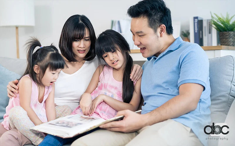 A family of four sitting on a sofa, admiring their maternity photoshoot together