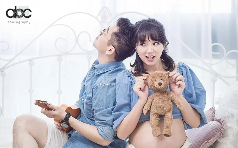 Indoor maternity photoshoot by abc photography featuring a teddy bear and ukulele as props