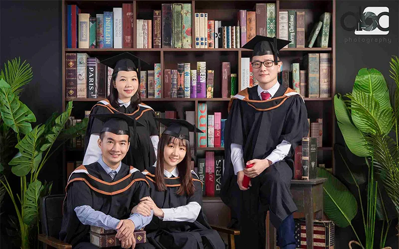 A group of students looking at the camera in their graduation gowns