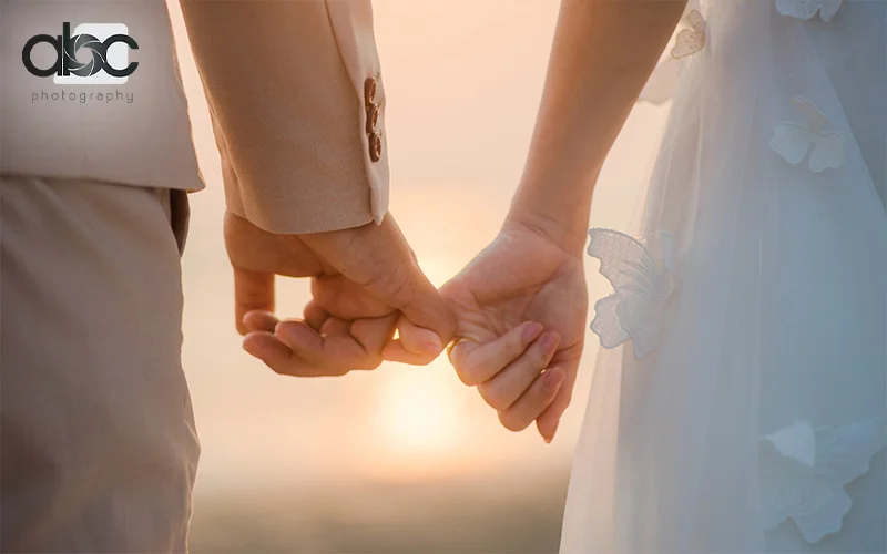 Newlywed couple interlocking their pinky fingers