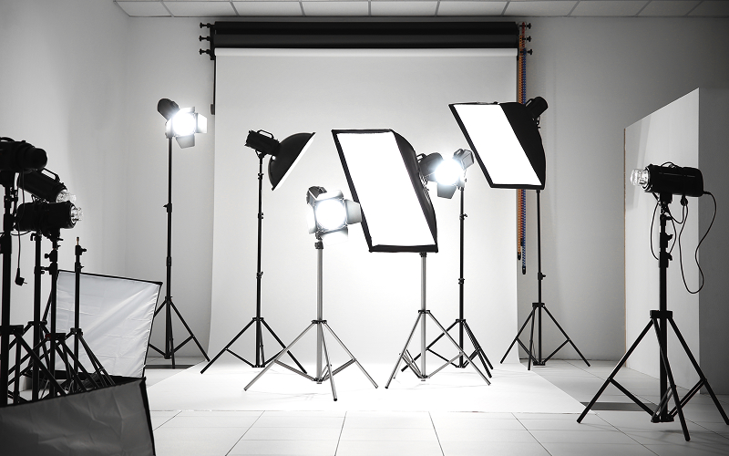 Professional photography studio with various softboxes and white backdrop.