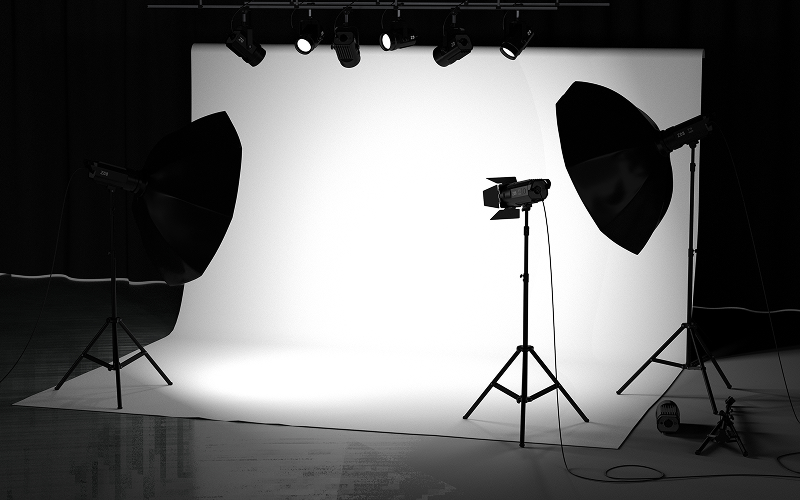 Studio lighting equipment positioned around a white photography backdrop.