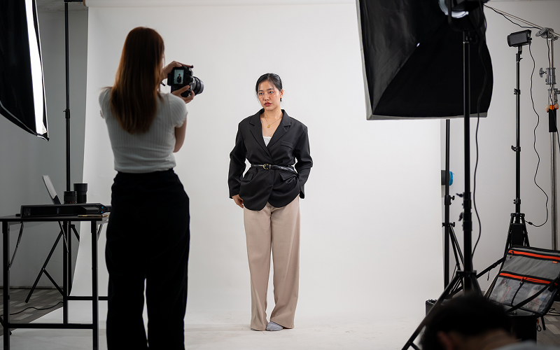 Photographer shooting a model against a white studio backdrop.