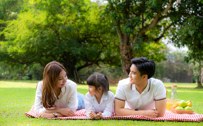 Family enjoying a lifestyle picnic photoshoot in a park.
