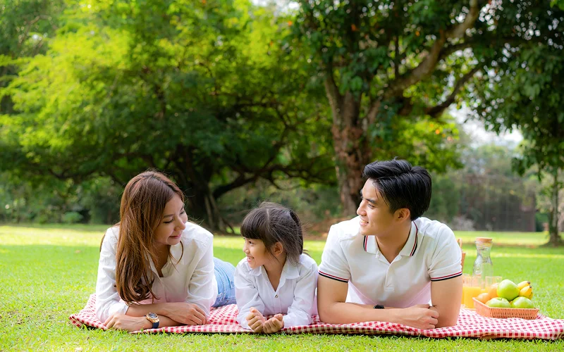 Family enjoying a lifestyle picnic photoshoot in a park.