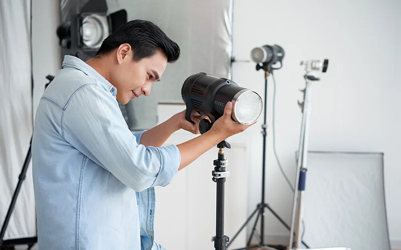 Person adjusting studio light in photography setup