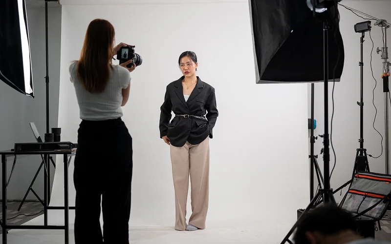Photographer shooting a model against a white studio backdrop.