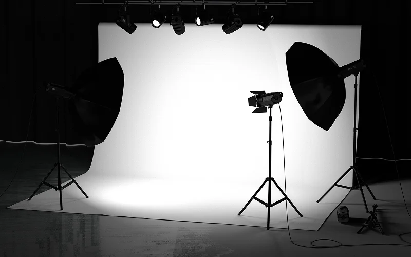 Studio lighting equipment positioned around a white photography backdrop.
