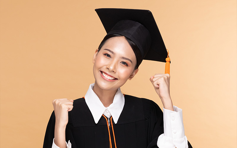 A smiling graduate wearing a cap and gown