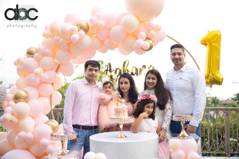 Family with first birthday balloon arch