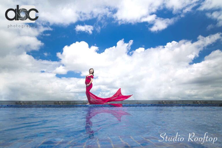 Rooftop pool maternity photoshoot with red gown
