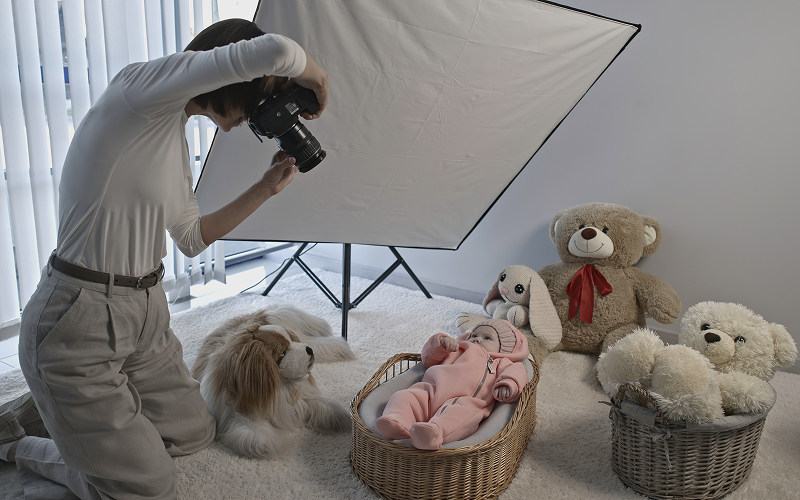 Professional photographer capturing newborn photos in a studio with softbox.