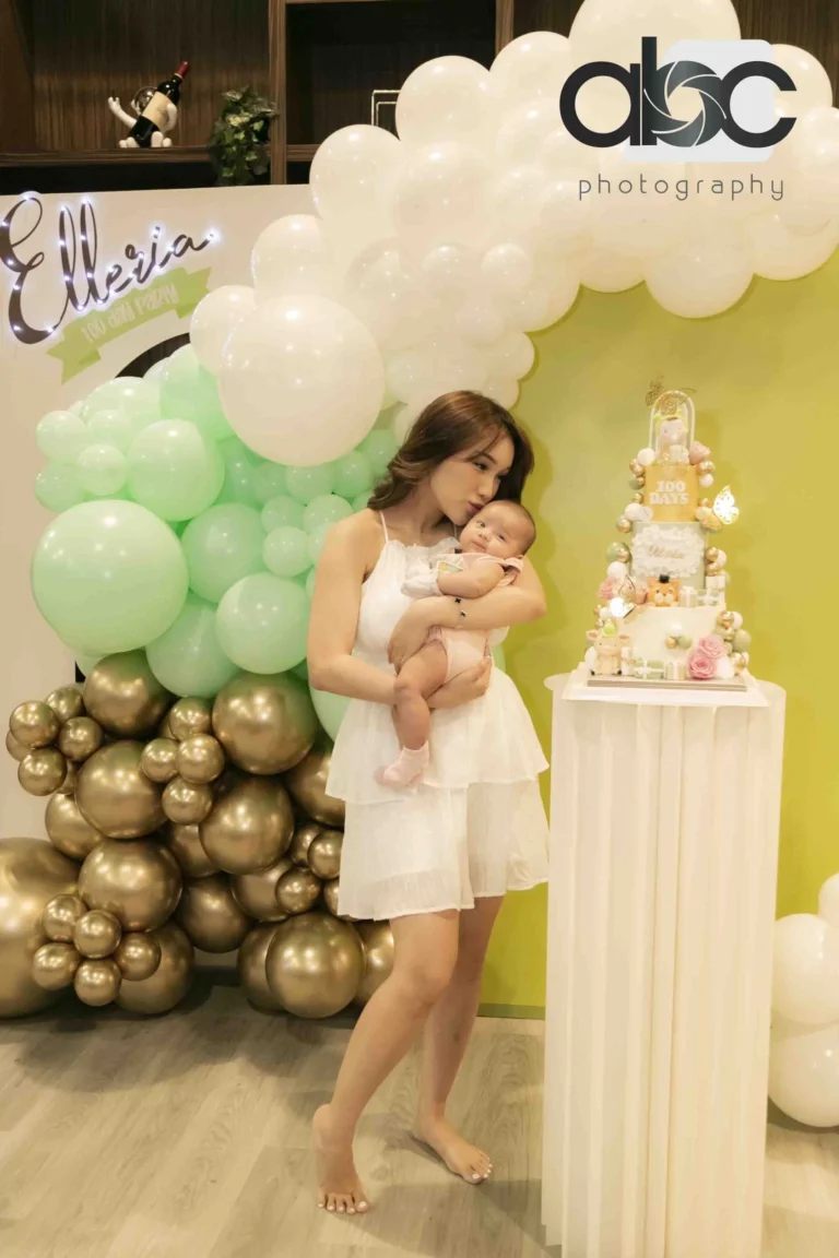 Mother holding baby by birthday cake